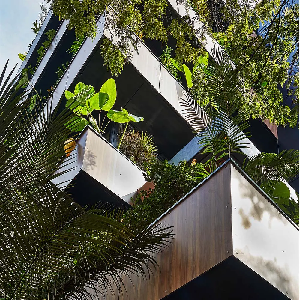 Un edificio en la zona rosa de medellín cargado de plantas tropicales y árboles