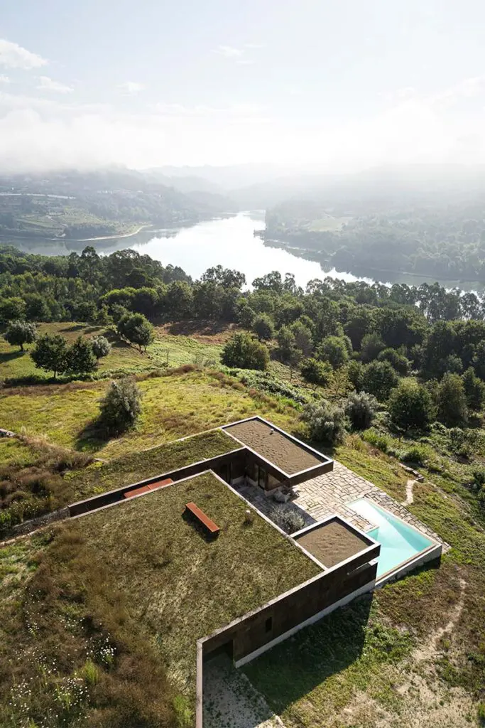 Una casa fundida en el paisaje de portugal: tiene cubiertas ajardinadas y muros de piedra