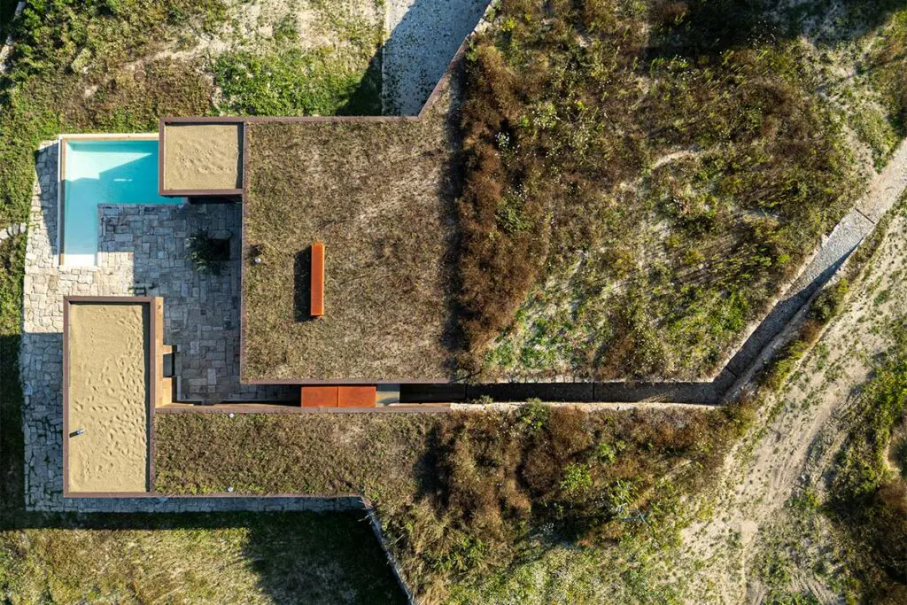 Una casa fundida en el paisaje de portugal: tiene cubiertas ajardinadas y muros de piedra