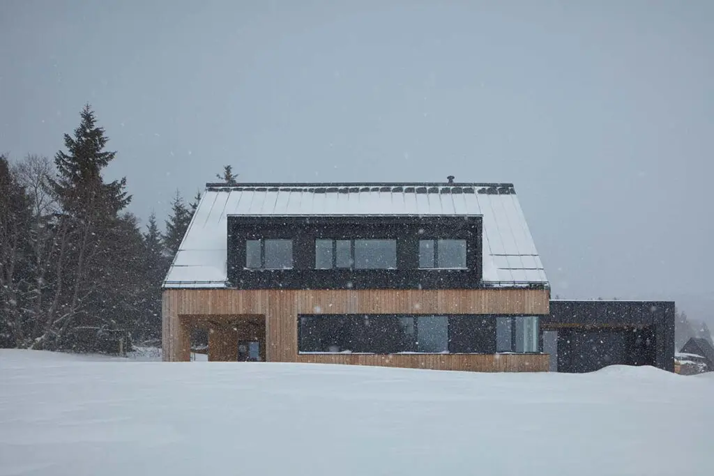 Una casa en la nieve con un diseño en armonía con la arquitectura local