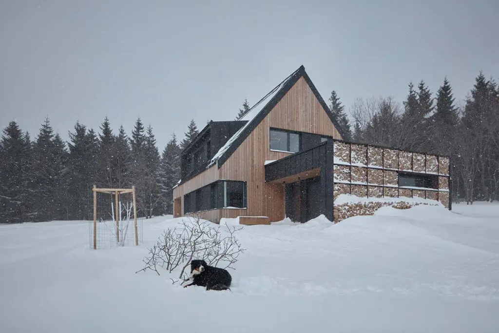 Una casa en la nieve con un diseño en armonía con la arquitectura local