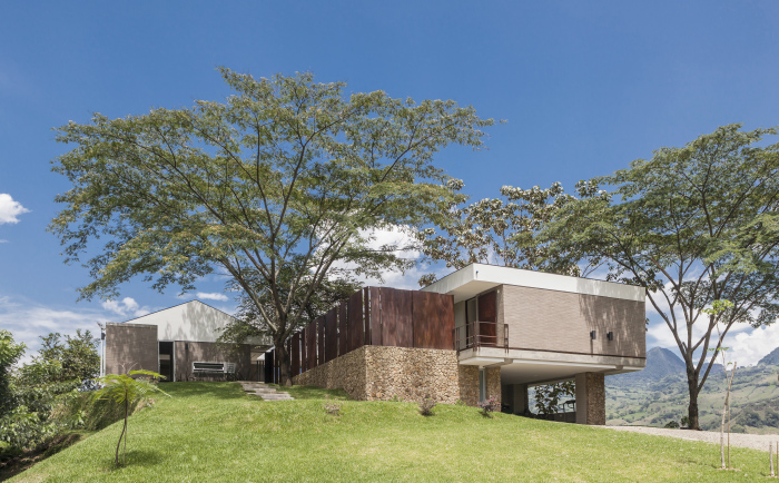 El basamento se resuelve mediante la construcción de muros de contención enchapados con la piedra resultante de las excavaciones. El color café rojizo y la textura burda de esta combina con los paneles de acero oxidado que delimitan y permiten la ventilación natural de la casa.