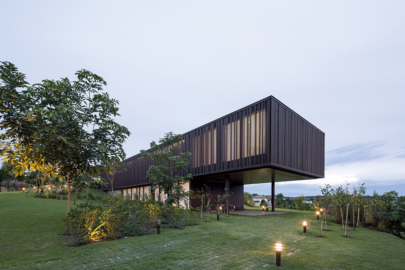 Hacia el lado occidente, la pendiente del terreno habilita la construcción de un nivel inferior. El volumen de planta baja se despega del suelo y vuela sobre el parqueadero al aire libre.
